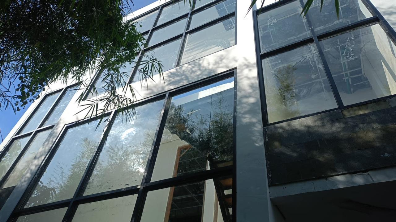 Shakiro Villas under construction, black-frame steel glazing installed, view looking up at the structure
